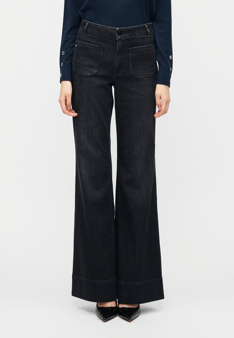 Τζιν με φαρδιές παντελόνες από σκούρο ντένιμ, διαθέτουν ψηλή μέση, μπροστινές τσέπες και καθαρό τελείωμα. Το ύφασμα έχει ομαλή υφή με ελαφριά ελαστικότητα.