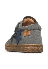 Scarpa in suede grigio con suola in gomma, caratterizzata da un accento a stella blu e una patch in cuoio marrone. Forma arrotondata, texture morbida.