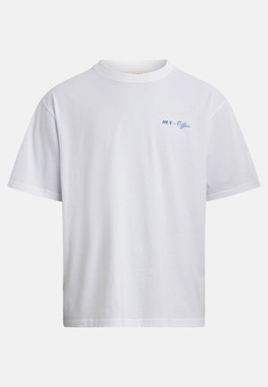 Maglietta bianca in cotone a maniche corte con piccolo testo blu "OUT of Office" sul petto a sinistra, mostrata su uno sfondo semplice.