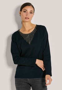 Schwarz langärmliges Shirt mit rundem Halsauschnitt und Verzierungen aus hängenden Perlen in V-Form am Hals. Weicher Stoff.
