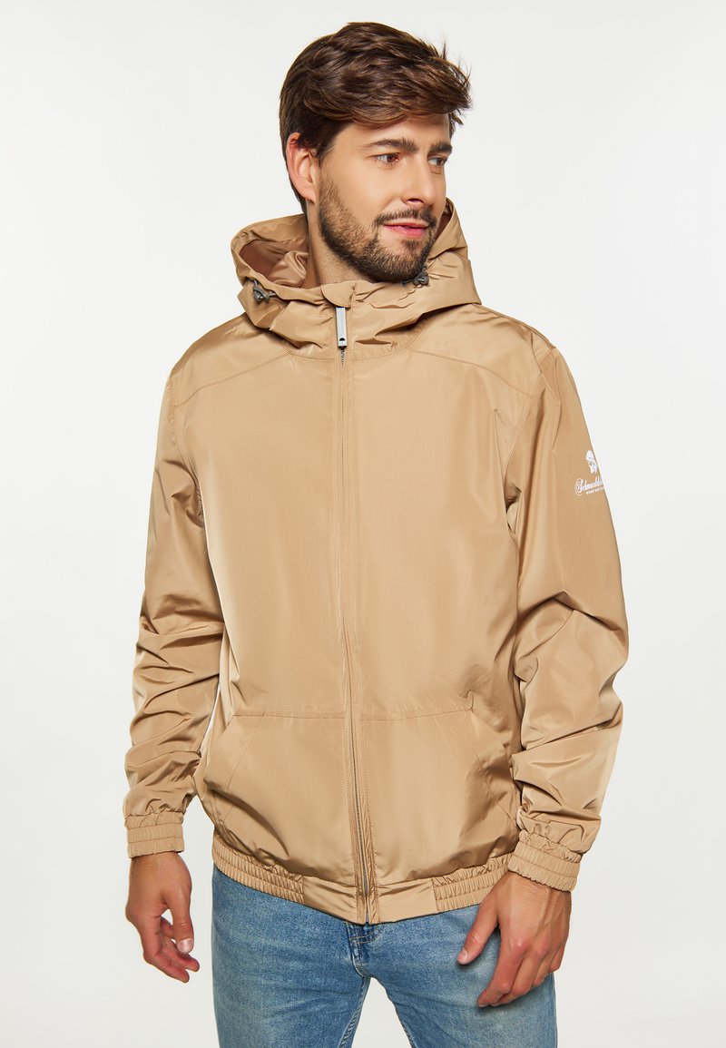 Beige lättviktig jacka med huva, framdragkedja och elastiska ärmslut. Slät textur med sidofickor och logodetalj på ärmen.