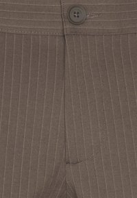 Bruin stikstofdoek met fijne verticale lijnen, voorzien van een voorste knoop met vier gaten en een klein zijzakdetail.