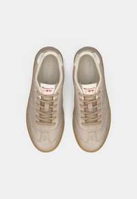 Μπεζ πάνινα παπούτσια σουέτ με λεία υφή, στρογγυλή μύτη και μπεζ κορδόνια, με λευκή γλώσσα που φέρει την επιγραφή "Tamaris" και καουτσούκ σόλα.