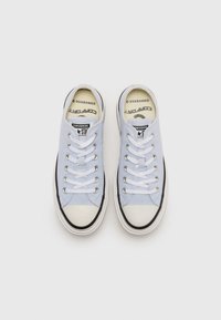 Light blue canvas sneakers with white laces, rubber toe cap, and black sole trim. Branding visible on the insole and outer side.