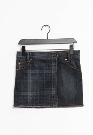 Dunkelblauer Denim-Minirock mit Patchwork-Design und ausgefranstem Saum, an einem schwarzen Kleiderbügel vor weißem Hintergrund hängend.