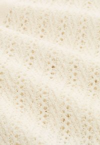 Crèmekleurige gebreide stof met een fijn kantpatroon met kleine gaatjes en verhoogde verticale strepen.