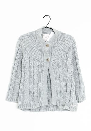 Cardigan tricoté gris clair avec des motifs torsadés, deux boutons et un large col côtelé suspendu à un cintre noir.