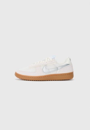 Niskoprofilne bijele i svijetloružičaste tenisice s mrežastim teksturama, smešnim gumenim đonom i metalik srebrnim Nike logom s boka na jednostavnoj pozadini.