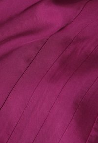 Fuksia-kangas, jossa on tasainen rakenne ja hienovarainen kiilto, sisältää pystysuoria raitamalleja ja pehmeää laskeutumista.