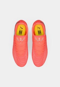 Φωτεινά ροζ αθλητικά παπούτσια με υφασμάτινη επιφάνεια, λεπτά κορδόνια, επενδυμένο κίτρινο πάτο και ανακλαστικές λεπτομέρειες στις πλευρές.