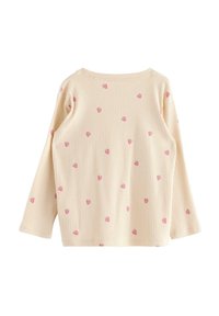 Pitkähihaista puseroa ribbikuvioisesta kermavärisestä kankaasta, jossa on pyöreä pääntie ja toistuva pieniä vaaleanpunaisia sydämiä sisältävä kuvio.