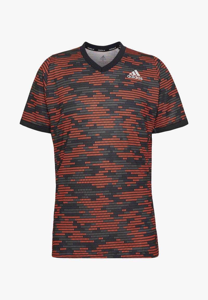 T-shirt de sport Adidas à manches courtes avec motif camouflage pixelisé noir et orange, col en V et logo Adidas sur la poitrine.