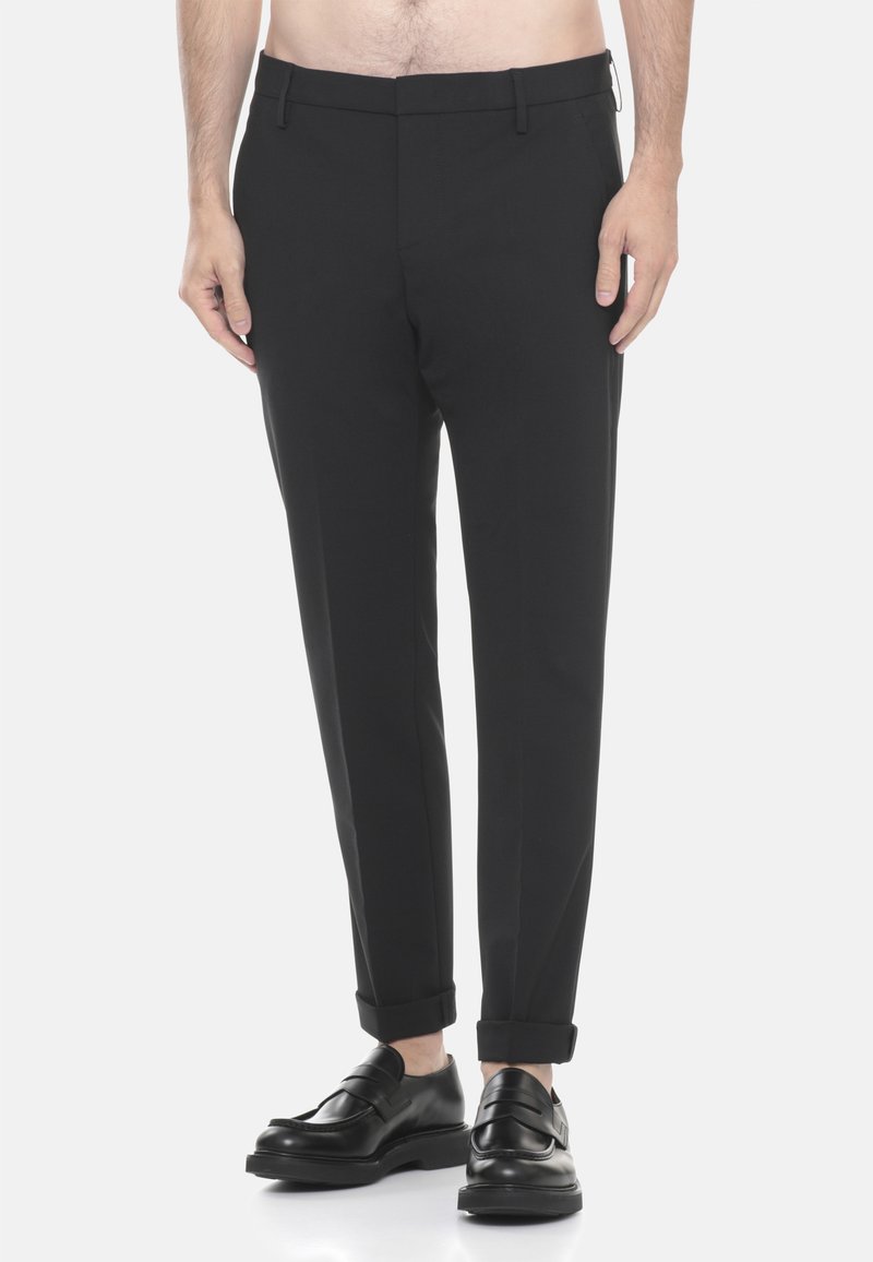 Pantaloni neri sartoriali con una vestibilità slim, caratterizzati da un davanti piatto, orli arrotolati e tessuto liscio. Indossati con mocassini neri.