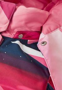 Jakke med et pink, glat ydre lag og abstrakte pink og marineblå mønstre på indersiden, sikret med sølvsnapper.