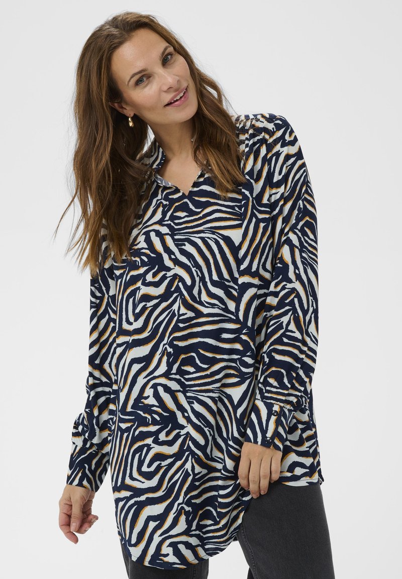 Langærmet bluse i navy, hvid og guld dyreprint. Har en krave, en løs og svævende pasform samt manchetter ved ærmerne.