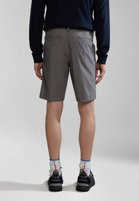 Grå lærredsshorts med regular fit, sidelommer og en baglomme, båret med sorte atletiske sko og multicolore sokker.