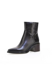 Bottine en cuir noir avec un talon carré bas et un bout légèrement pointu, présentée sur fond blanc.