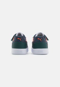 Baskets Puma avec une tige en cuir vert foncé et bleu marine, semelle en caoutchouc blanche et accents orange ; dispose d'une lanière à fermeture auto-agrippante.
