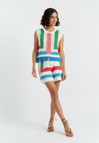 Ensemble en crochet composé d'un top sans manches et d'un short. Les couleurs incluent le blanc, le vert, le bleu, le rose et le rouge en rayures horizontales.