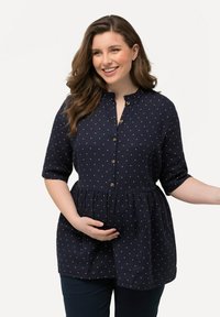 Blusa blu navy con pois bianchi, maniche a metà, apertura con bottoni e vita arricciata per un fit rilassato. Tessuto morbido.