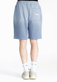 Lysblå shorts med elastisk talje, baglomme og hvidt logo-detalje. Glat stoftekstur, længde til midten af låret.
