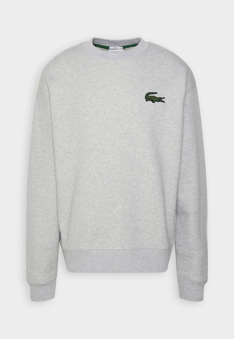 Sudadera gris hecha de un material suave, con cuello redondo, puños acanalados y un pequeño logo de cocodrilo bordado en verde en el pecho.