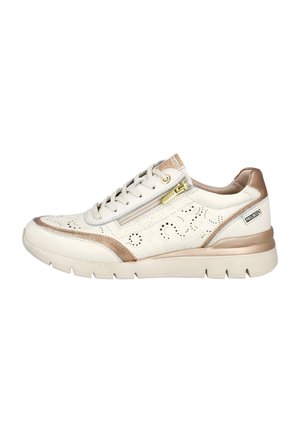 Zapatilla blanca y beige con diseño perforado, detalles dorados metálicos y ribete marrón claro. Cuenta con cierre de cordones y suela texturizada.