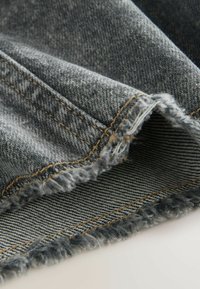 Halli denim kangas, millel on narmendav serv, kollaste õmblustega ja peene triibulise mustriga allosas. Struktuurne, vastupidav materjal.