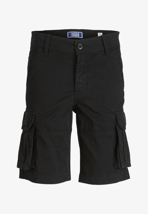 Person iført en rustfarvet kortærmet skjorte med knapper, sorte cargoshorts, hvide sokker og sort-hvide sneakers, stående på en hvid baggrund.