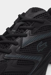 Μαύρο αθλητικό παπούτσι με λεπτομέρειες από δίχτυ, μαύρα κορδόνια και σκούρο μπλε ριγέ σχέδιο με λογότυπο κροκοδείλου στο πλάι.