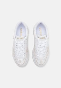 Adidași albi cu design perforat, accente metalice, șireturi albe și guler umplut, având logo-ul brandului în aur pe limbă.