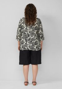 Zwart-witte gebloemde blouse met driekwartmouwen, gecombineerd met losse zwarte shorts. Gemaakt van lichtgewicht stof, met een relaxte pasvorm.