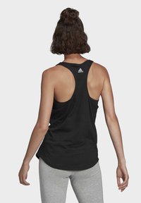 Svart atletisk linne med racerback-design, tillverkat av lätt tyg. Har en liten vit Adidas-logotyp på baksidan.