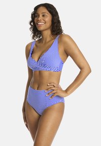 Costume da bagno a righe blu e bianche, composto da un top a scollo a V con spalline larghe e uno slip alto in vita, realizzato in tessuto morbido ed elastico.