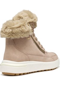 Bottines en suède beige avec un col en fourrure, des accents de fermeture éclair dorés et une épaisse semelle en caoutchouc blanc avec une adhérence texturée en brun.