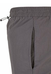 Shorts légers gris avec une taille élastique, un cordon de serrage et une poche latérale. Texture lisse et design simple pour une tenue décontractée.