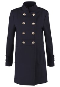 Cappotto doppiopetto blu navy con bottoni argentati, colletto alto, tasche laterali e vestibilità sartoriale. Realizzato in un tessuto liscio e strutturato.