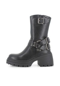 Botines negros con suela de plataforma gruesa, que presentan una textura similar al cuero suave, dos correas ajustables y un detalle de hebilla lateral.