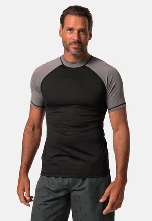 Krótki rękaw rash guard wykonany z gładkiej czarnej tkaniny z szarymi rękawami raglanowymi. Posiada okrągły dekolt i dopasowany krój, idealny do aktywności fizycznej.