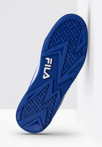 Zilā gumijas apavu zole ar zigzaga rakstu, strukturētu saķeri un baltu Fila logotipu. Sānu daļai ir gluda virsma, kas pāriet uz zoli.