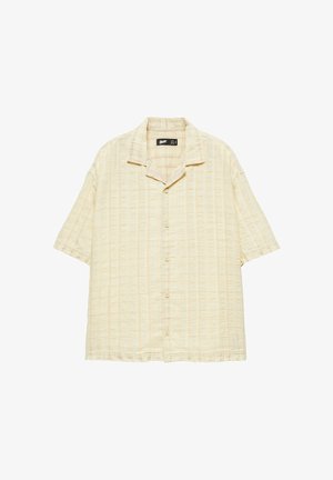 Chemise beige à manches courtes avec un motif subtil à rayures verticales et un col camp, présentée sur un fond blanc.