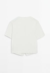 Haut à manches courtes en tissu gris clair avec une coupe droite, doté d'une couture au dos et d'un ourlet fendu sur les côtés pour faciliter les mouvements.