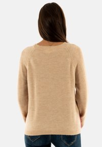 Suéter de punto beige con mangas largas, escote redondo y un corte relajado. Textura suave con un patrón mínimo y un dobladillo recto.
