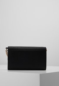 Bolso rectangular negro con un acabado texturizado, cadena dorada y cierre de solapa. Diseño simple sin patrones ni acentos visibles.
