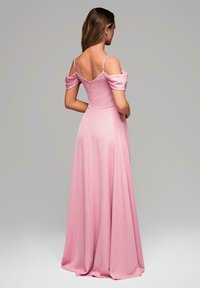 Lång rosa kvällsklänning med off-the-shoulder ärmar och en figursydd bodice. Tyget är mjukt med en lätt lyster och flödar ut i en full kjol.