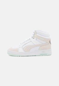 High-top sneaker with a white leather upper and beige suede accents. Features perforated toe box and light green rubber sole.