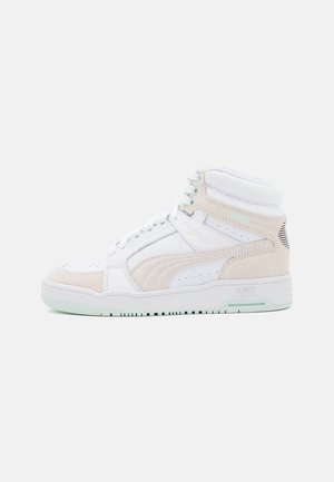 Baskets montantes avec une tige en cuir blanc et des accents en suède beige. Elles présentent une boîte à orteils perforée et une semelle en caoutchouc vert clair.