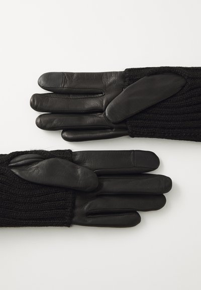 Sorte hansker med lærpalmer og strikkede mansjetter. Hanskene har et strukturert, ribbet design med tillegg av lærdetaljer.