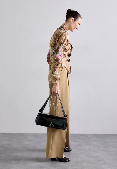 Blouse texturée marron avec des imprimés colorés, pantalon beige à jambes larges, et sac à main noir brillant avec des chaînes.