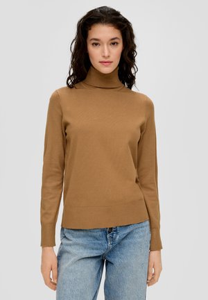 Pull à col roulé marron fabriqué dans un matériau côtelé, avec des manches longues et une coupe ajustée, associé à un jean bleu clair.